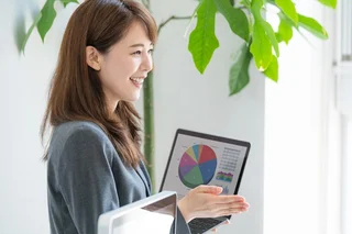 Young woman smiling and holding a laptop with pie charts on the screen