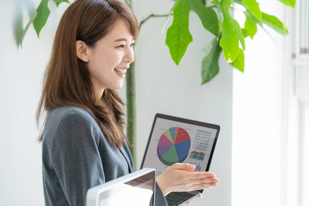 Young woman smiling and holding a laptop with pie charts on the screen