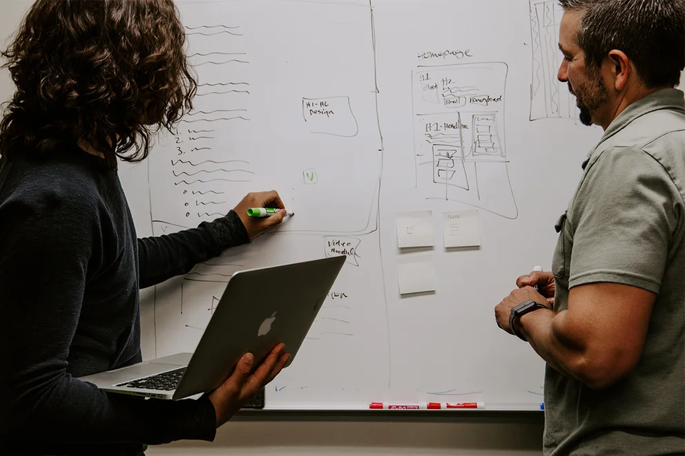 Man and woman writing on a whiteboard.