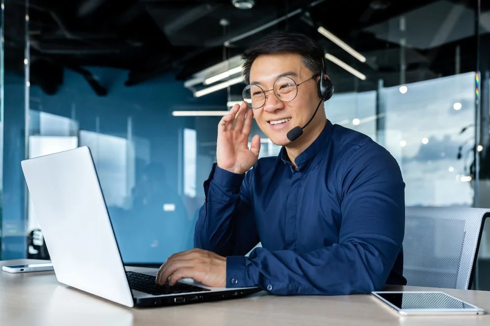 Person wearing a headset working on a laptop in a modern office environment.