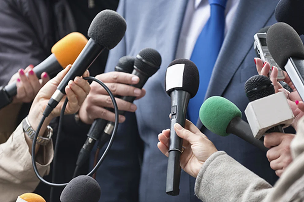 Close up of many microphones in front of a man wearing a business suit