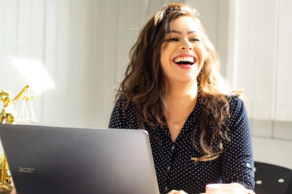 Smiling woman sat at her laptop.