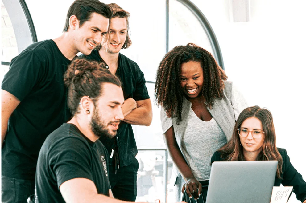 A group of colleagues looking at a laptop together