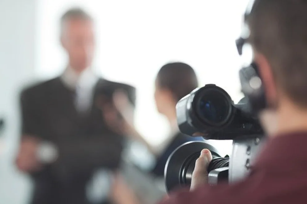 Close up of a camera operator recording a man in a business suit