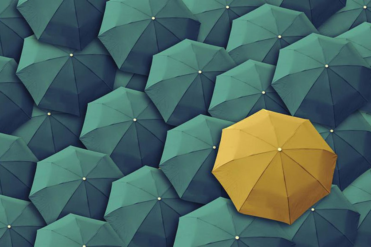 Yellow umbrella surrounded by green umbrellas