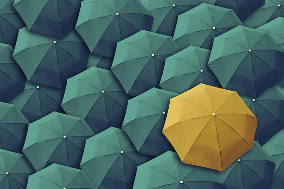 Yellow umbrella surrounded by green umbrellas