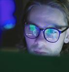 Young person with glasses in front of a laptop screen