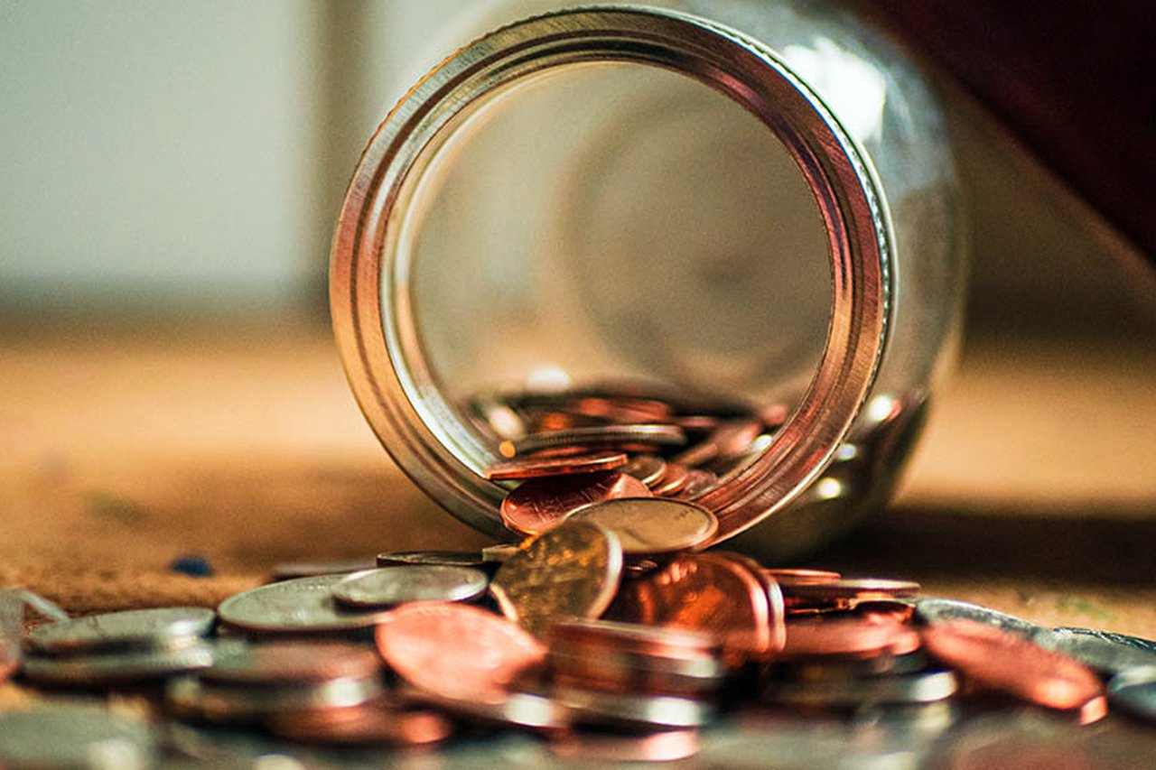 Money tipping out of a jar.