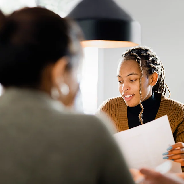 Two young people sitting at a desk reviewing some papers