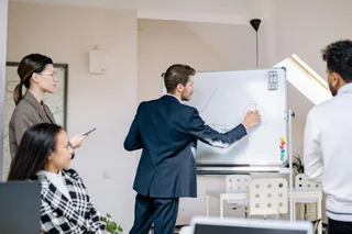 A man presenting on the board to his colleagues