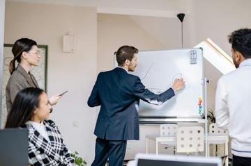 A man presenting on the board to his colleagues