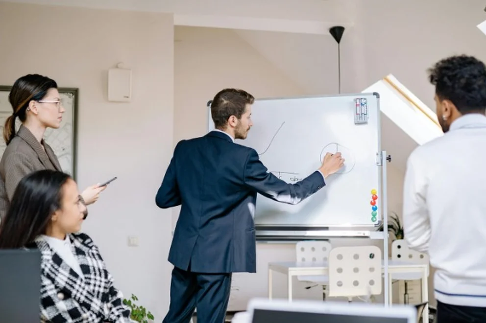 A man presenting on the board to his colleagues