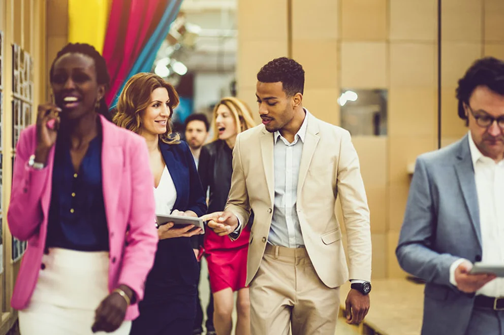 Two people wearing business suits walking and chatting
