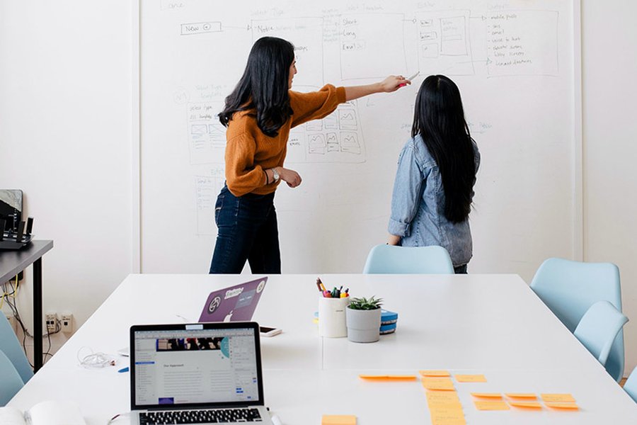 Two women in an office discuss plans.