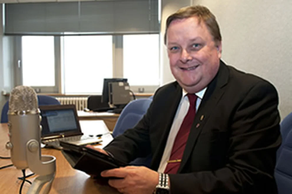Man sitting at a desk holding a tablet and smiling