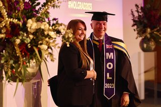 Khaled Shaker is shaking hands with Melanie Nicholson, Managing Director of MOL, at the MOL graduation ceremony. They are on stage.