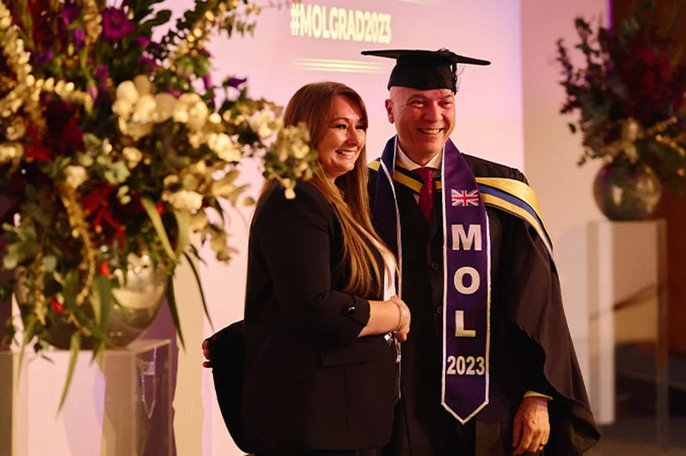 Khaled Shaker is shaking hands with Melanie Nicholson, Managing Director of MOL, at the MOL graduation ceremony. They are on stage.