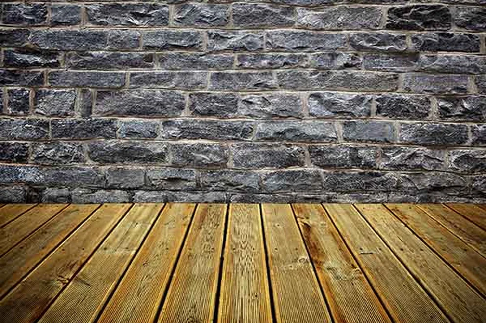 A wall of dark bricks and a wooden floor