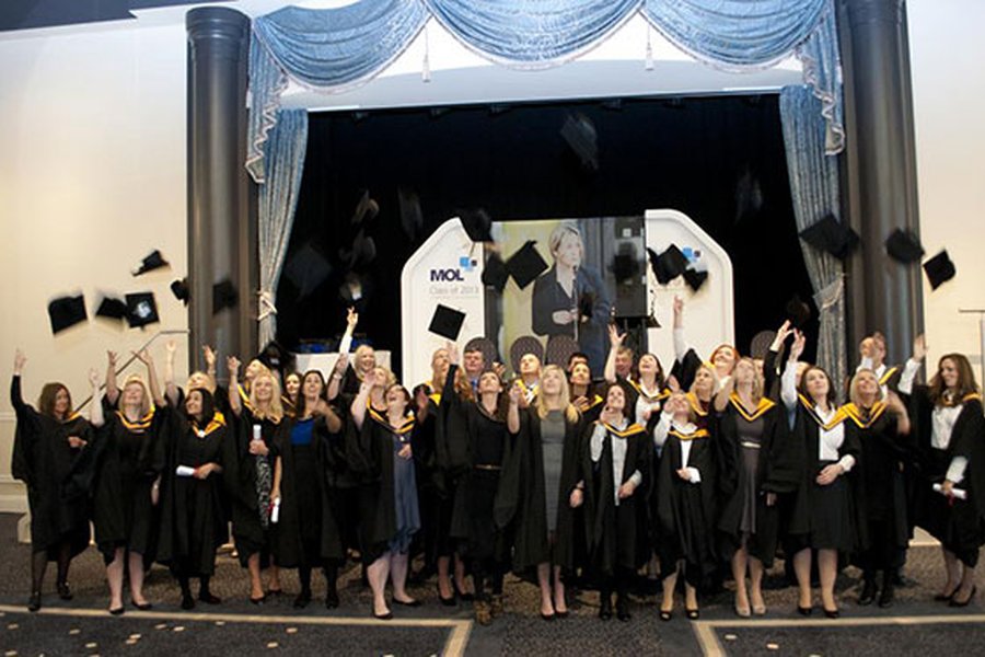 Graduates celebrate by throwing their mortarboards into the air