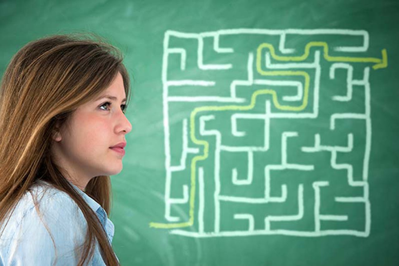 Woman standing next to chalkboard maze