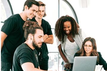 A group of colleagues looking at a laptop together