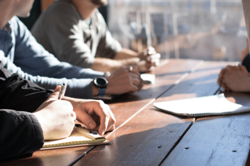 Close up of hands of a group of people sitting at a wooden table and chatting