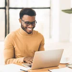 Smiling young man working on a laptop computer