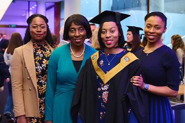 Margaret Quarshie, dressed in graduation robes, poses for a picture with her family at the MOL graduation ceremony.