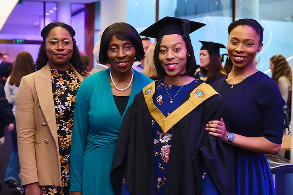 Margaret Quarshie, dressed in graduation robes, poses for a picture with her family at the MOL graduation ceremony.