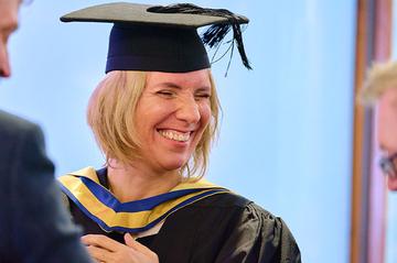 A candid picture of Maricel Champion who is wearing her cap and gown, and smiling at the MOL graduation ceremony.