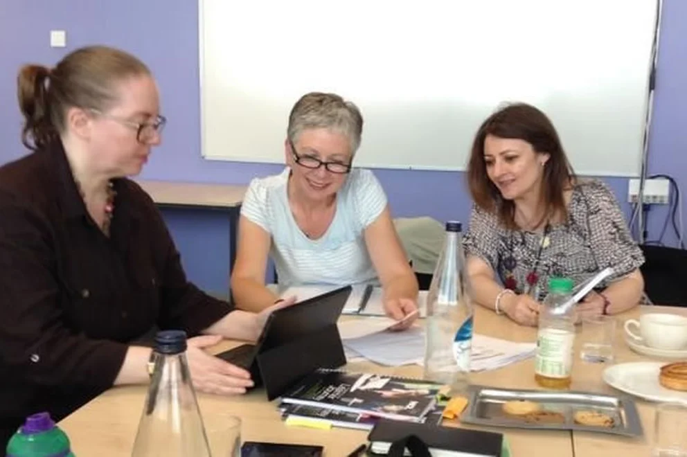 People working collaboratively at a table and looking ad a tablet