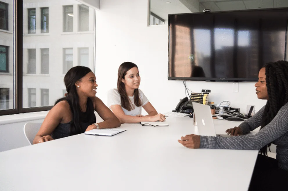 Three women sitting at a desk in an office working together