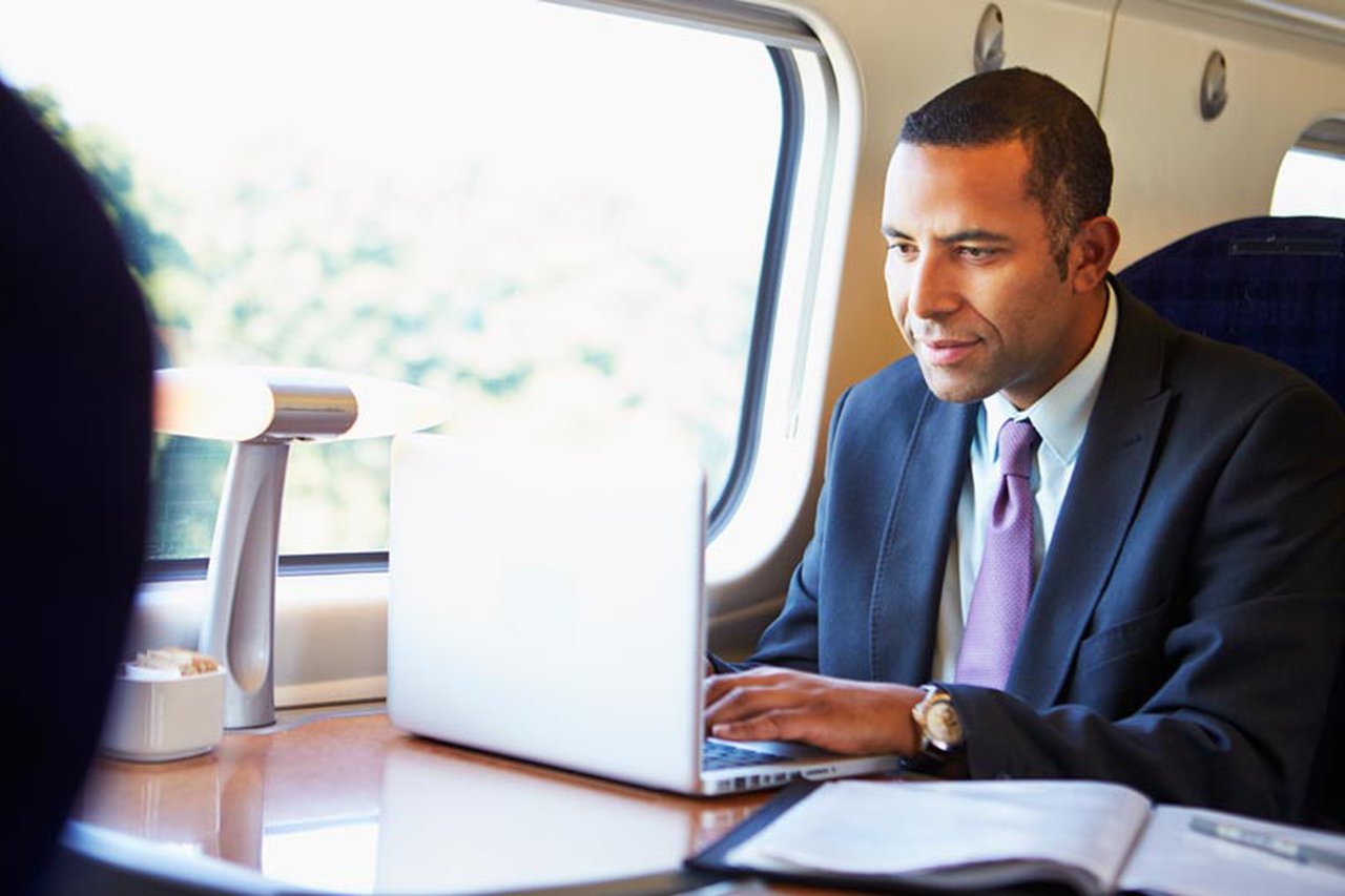 Man on a train working on a laptop