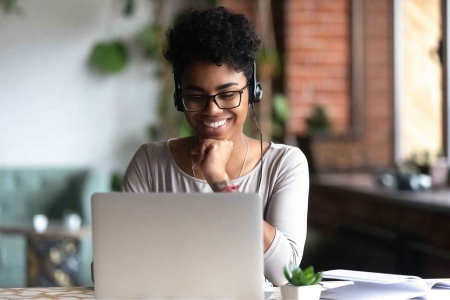 Woman wearing glasses and headphones and working on a laptop computer