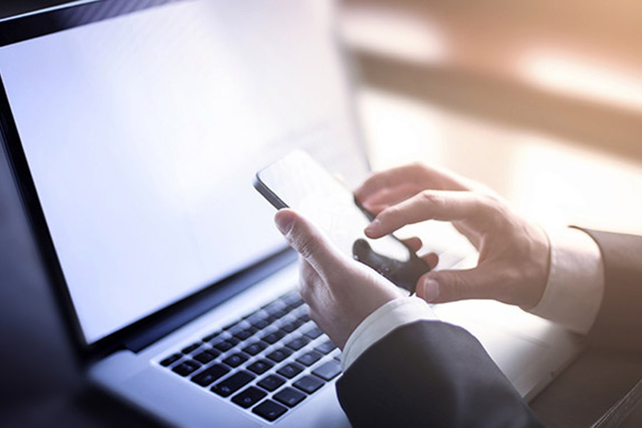 Business professional using a laptop and a phone