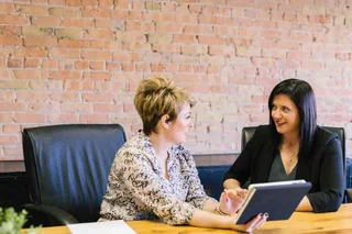 Two women in front of a brick wall.