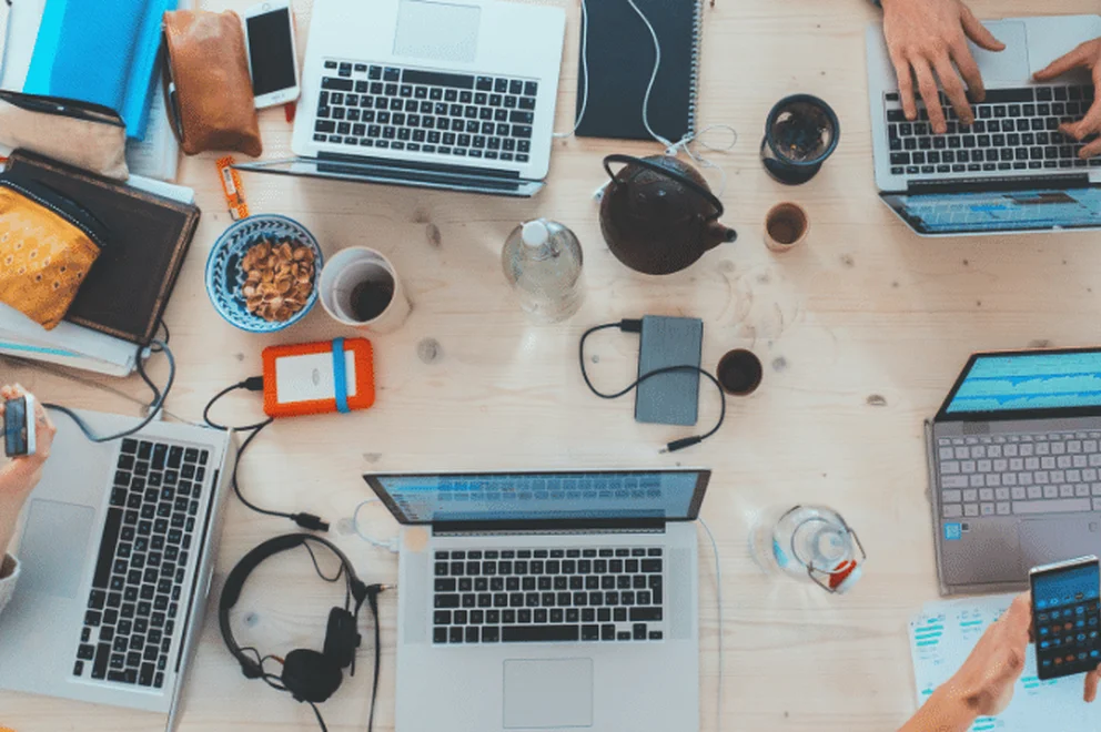 Close up picture of hands of many people working collaboratively with computers at a table