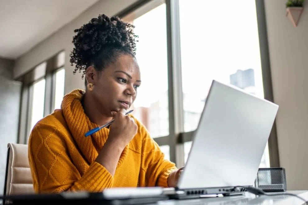 A woman sat on the desk looking at her laptop